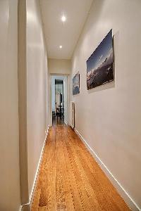 hallway with wooden floors and paintings in a 3-bedroom Paris luxury apartment