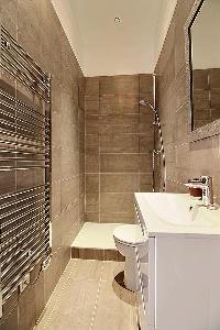 sleek bathroom with sink, bathroom cabinet, mirror, toilet, and shower area in a 3-bedroom Paris lux