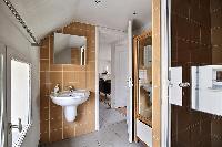 bathroom fully-equipped with a toilet, a sink, a mirror, and a shower area in a 2-bedroom Paris luxu