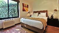 first bedroom furnished with a queen-size bed, and two bedside tables with lamps in a 2-bedroom pari