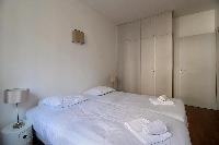 second bedroom with two single beds joined together, a television, and a nightstand in Paris luxury 