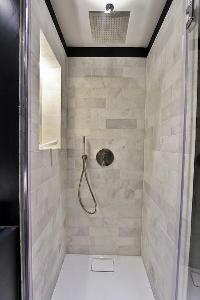 an en-suite bathroom with a toilet, a sink, a mirror, and a shower area in a 2-bedroom Paris luxury 