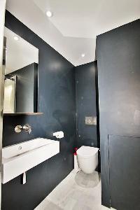 an en-suite bathroom with a toilet, a sink, a mirror, and a shower area in a 2-bedroom Paris luxury 