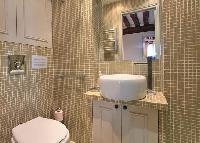 an en-suite bathroom with toilet, sink, mirror, cabinet, and a shower area in a 2-bedroom Paris luxu