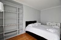 second bedroom with shelves and a Double bed in a 3-bedroom Paris luxury apartment