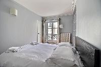 second bedroom with shelves and a Double bed in a 3-bedroom Paris luxury apartment