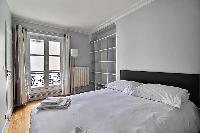 second bedroom with shelves and a Double bed in a 3-bedroom Paris luxury apartment
