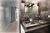 a full bathroom with an open shower, bathtub, double sink and a toilet in a 2-bedroom Paris luxury a