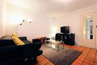 living area with comfortable sofa,TV, night stand, glass center table, and slate grey carpet rug in 