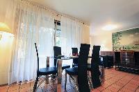 modern dining area for 6 with glass dining table and tall French windows in a 3-bedroom Paris luxury