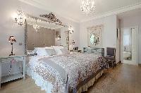 elegant bedroom with queen size bed, bedside tables, lamps, wide mirror, and en suite bathroom in a 