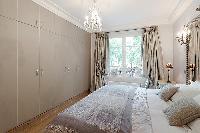 elegant bedroom with queen size bed, bedside tables, lamps, and closets in a 3-bedroom Paris luxury 