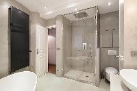 elegant bathrooms with sinks, shower, bathtub and toilet in a 3-bedroom Paris luxury apartment