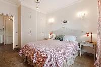 second bedroom with queen size bed, bedside tables, lamps, and closets in a 3-bedroom Paris luxury a