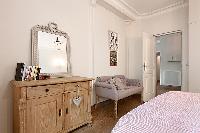 elegant bedroom with queen size bed, armchair, mirror, and cabinet in a 3-bedroom Paris luxury apart