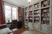 study room with a sofa bed and bookshelves in a 3-bedroom Paris luxury apartment