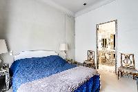 chic bedroom with television and bright windows with drape curtain in paris luxury apartment