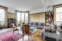 classy living area with grey sofas, armchairs and floor-to-ceiling windows overlooking the street in