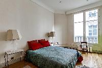 chic bedroom with lamp, bright windows, and drape curtain in a 3-bedroom paris luxury apartment