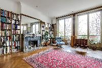 classy living area with fireplace, mirror, reclining chair, books-filled bookshelves, and bright Fre