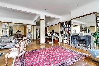 classy living area with fireplace, mirror, reclining chair, and books-filled bookshelves in a 3-bedr