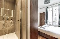 Bedroom with a queen size bed and an en-suite bathroom with a standing shower, toilet and sink in a 