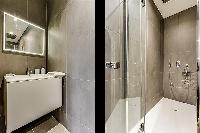 an en-suite bathroom with a standing shower, toilet and sink in a 1-bedroom Paris flat