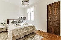 Bedroom with Queen size bed, bedside tables, and lamps in a 2-bedroom Paris luxury apartment