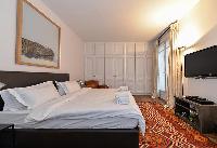 elegant master bedroom with king sized bed, HD TV, leather couch, closet, French wndow and drape cur