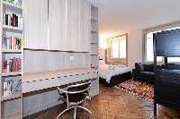 cozy bedroom with a couch, study table, bookshelves, and ample storage in paris luxury apartment