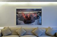a long taupe sofa with pillows and a work of art hanged on a white wall in paris luxury apartment