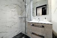 lovely and neatly-stocked bathroom with a shower and sink in a 2-bedroom Paris luxury apartment