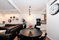 cozy dining area with an elegant and shiny round dining table with chairs in a 2-bedroom Paris luxur