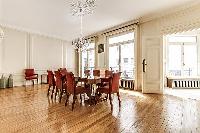 elegant dining room with long, rectangular dining table with 8 seats and tall bright windows, and ch