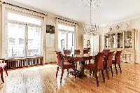 elegant dining room with long, rectangular dining table with 8 seats and tall bright windows, and ch