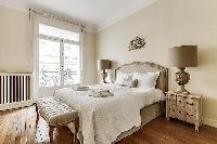 bedroom  with queen-sized bed, varying duvet colors and room wall decals in a 4-bedroom Paris luxury