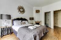 bedroom  with queen-sized bed, varying duvet colors and room wall decals in a 4-bedroom Paris luxury