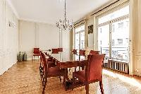 elegant dining room with long, rectangular dining table with 8 seats and tall bright windows, and ch