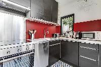 fully-equipped red and grey kitchen in a Paris luxury apartment