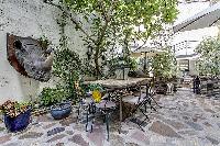 relaxing courtyard with table and chairs, and potted plants in a Paris luxury apartment