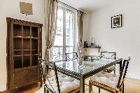 dining area highlighted by a glass table with 4 matching seats in a Paris luxury apartment