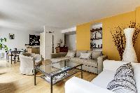 cozy living room with rich yellow walls, two Scandinavian-style double-sized sofa beds, and entertai