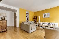 cozy living room with rich yellow walls, two Scandinavian-style double-sized sofa beds, and entertai