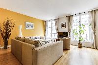 cozy living room with rich yellow walls, two Scandinavian-style double-sized sofa beds, and entertai