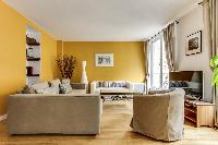 cozy living room with rich yellow walls, two Scandinavian-style double-sized sofa beds, and entertai