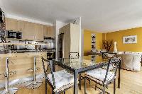 dining area highlighted by a glass table with 4 matching seats in a Paris luxury apartment