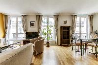 dining area highlighted by a glass table with 4 matching seats in a Paris luxury apartment