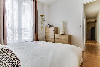 cozy bedroom with queen-sized beds, ample closet space, and drawers in a Paris luxury apartment