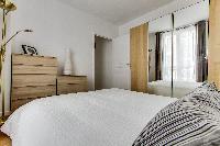 cozy bedroom with queen-sized beds, ample closet space, and drawers in a Paris luxury apartment
