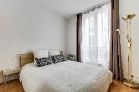 cozy bedroom with queen-sized beds, ample closet space, and drawers in a Paris luxury apartment